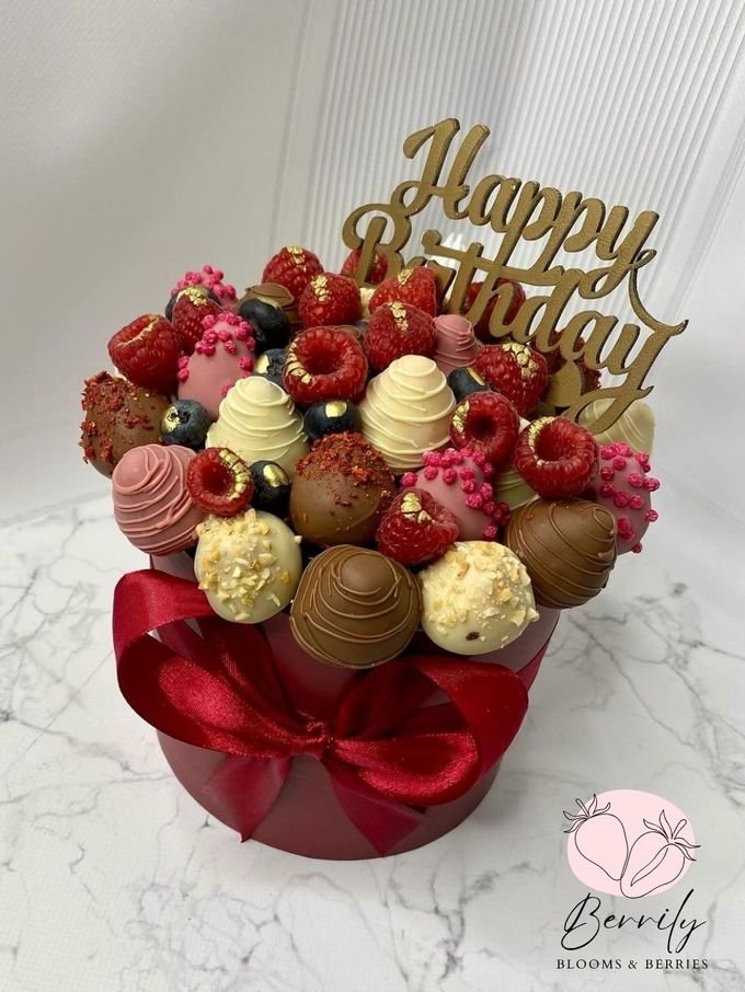 Bouquet de cumpleaños en caja redonda roja con fresas, raspberries y blueberries cubiertas de chocolate