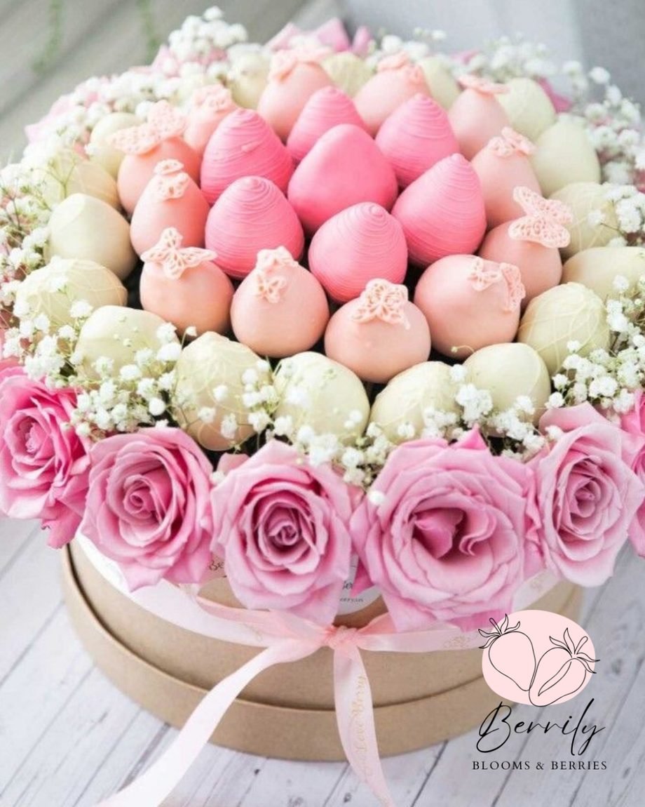 Caja redonda con fresas cubiertas de chocolate en tonos rosa y blanco, mariposas de azúcar y rosas