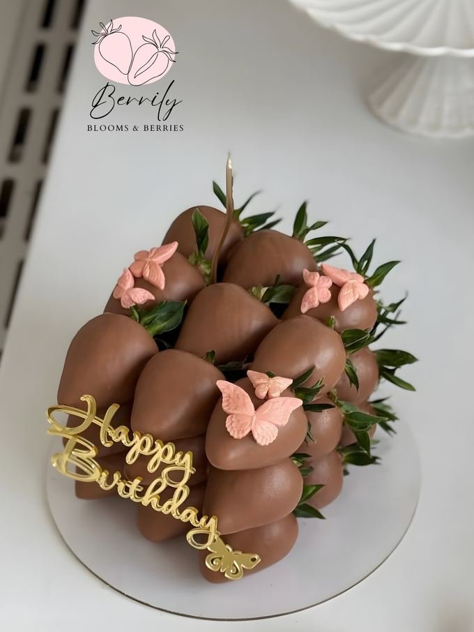 Torre de fresas cubiertas de chocolate con mariposas de azúcar y topper dorado de cumpleaños